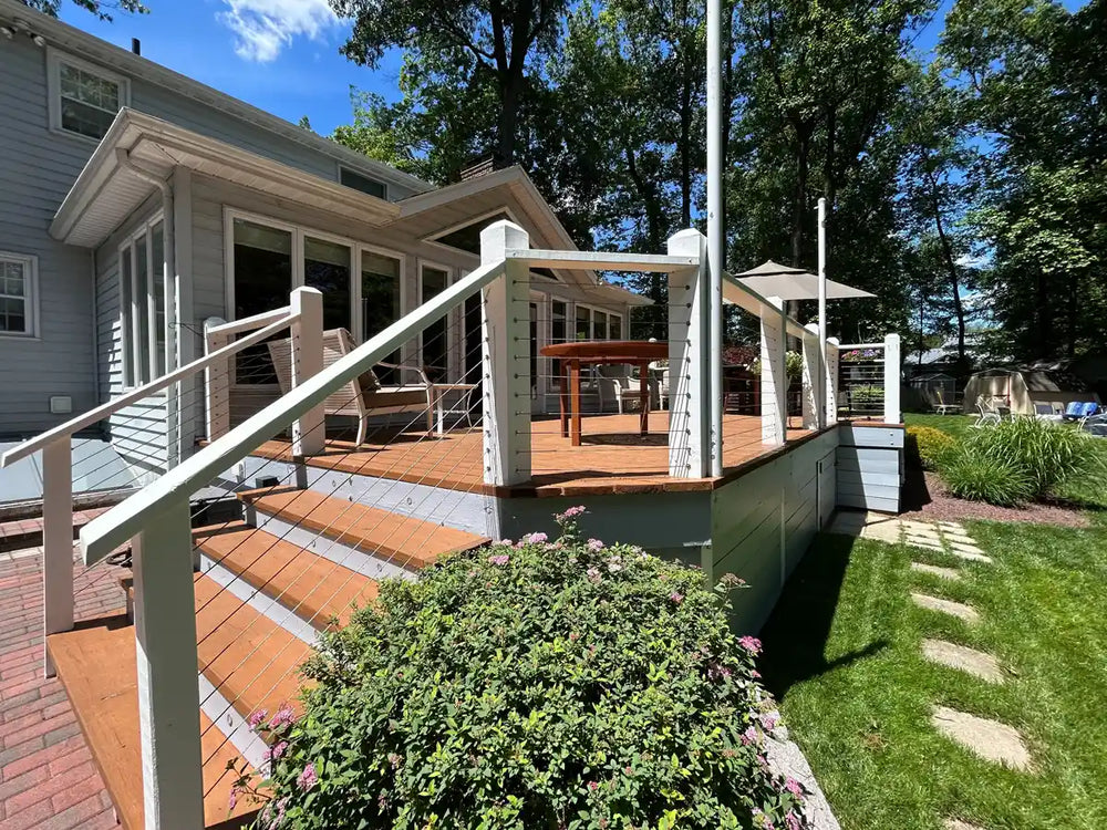 A sunny backyard wood deck with cable railing opening to the garden
