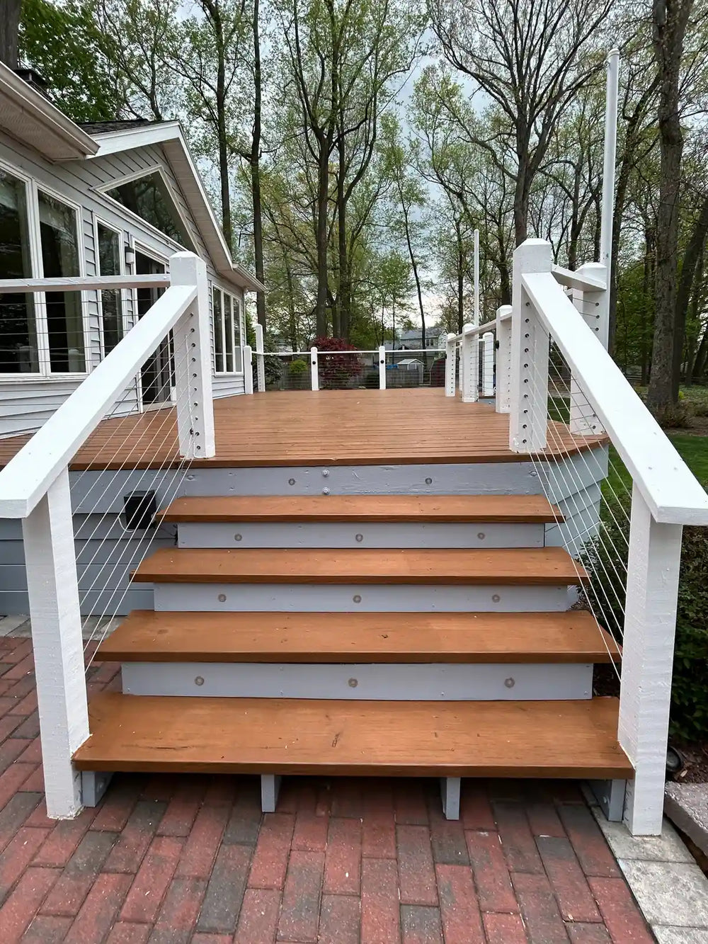 A welcoming backyard deck with stairs, featuring warm wood tones and cable railing