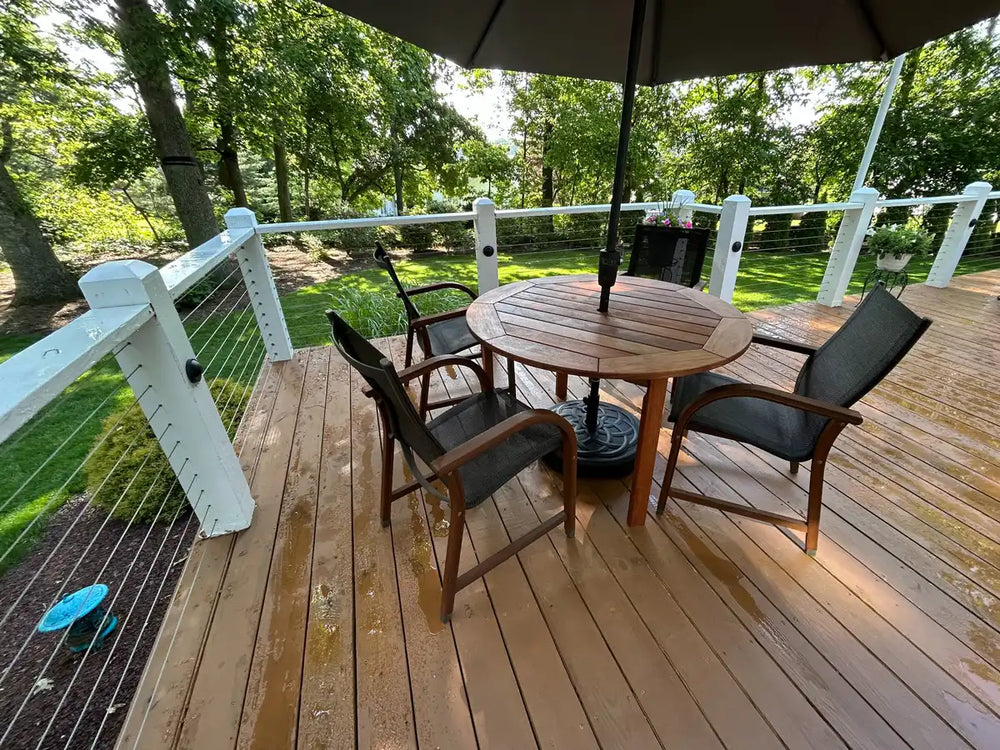 An outdoor dining area on the wood deck, framed by sleek cable railing