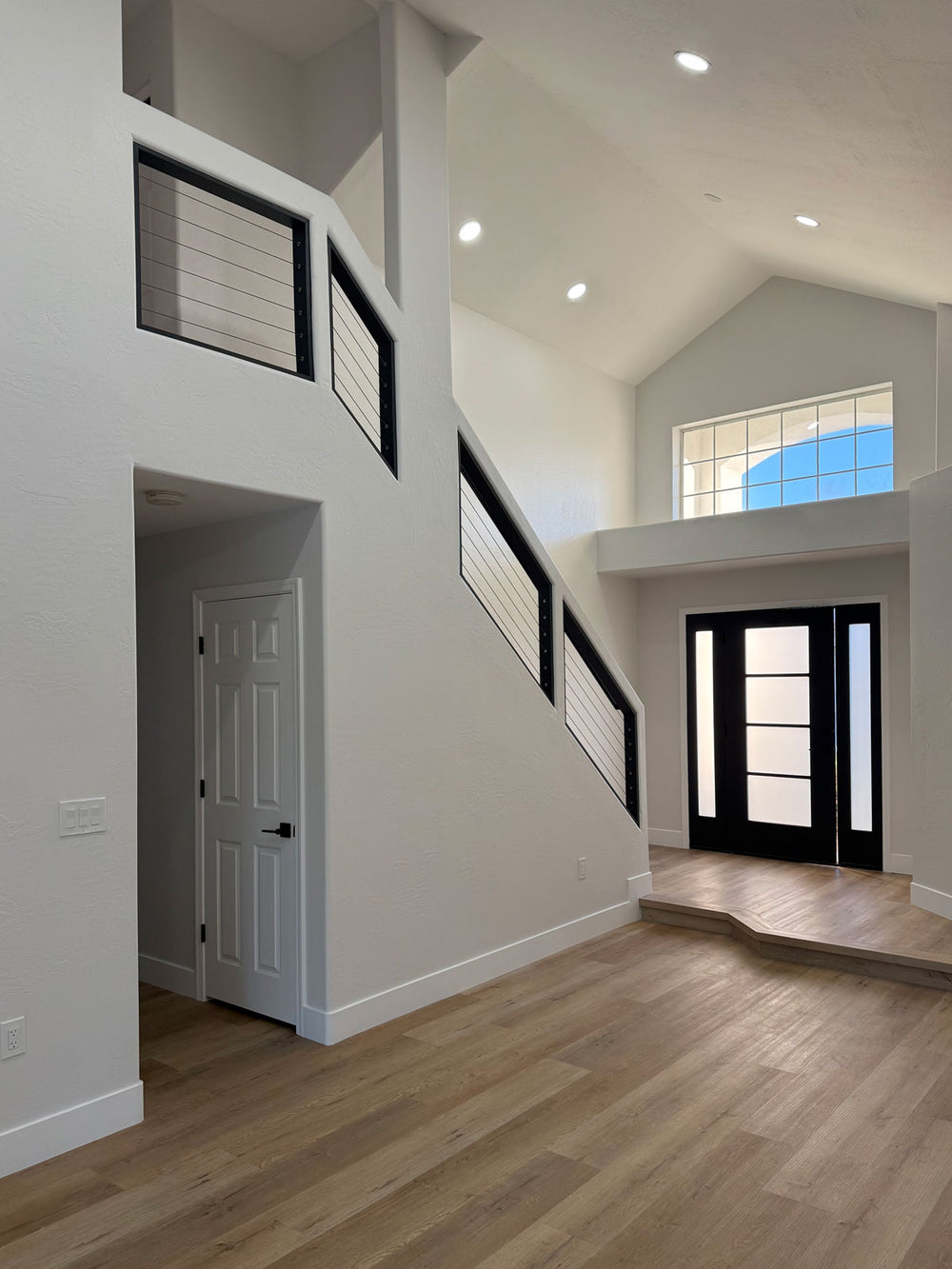 black cable stair railing defining the staircase within a bright open entry area