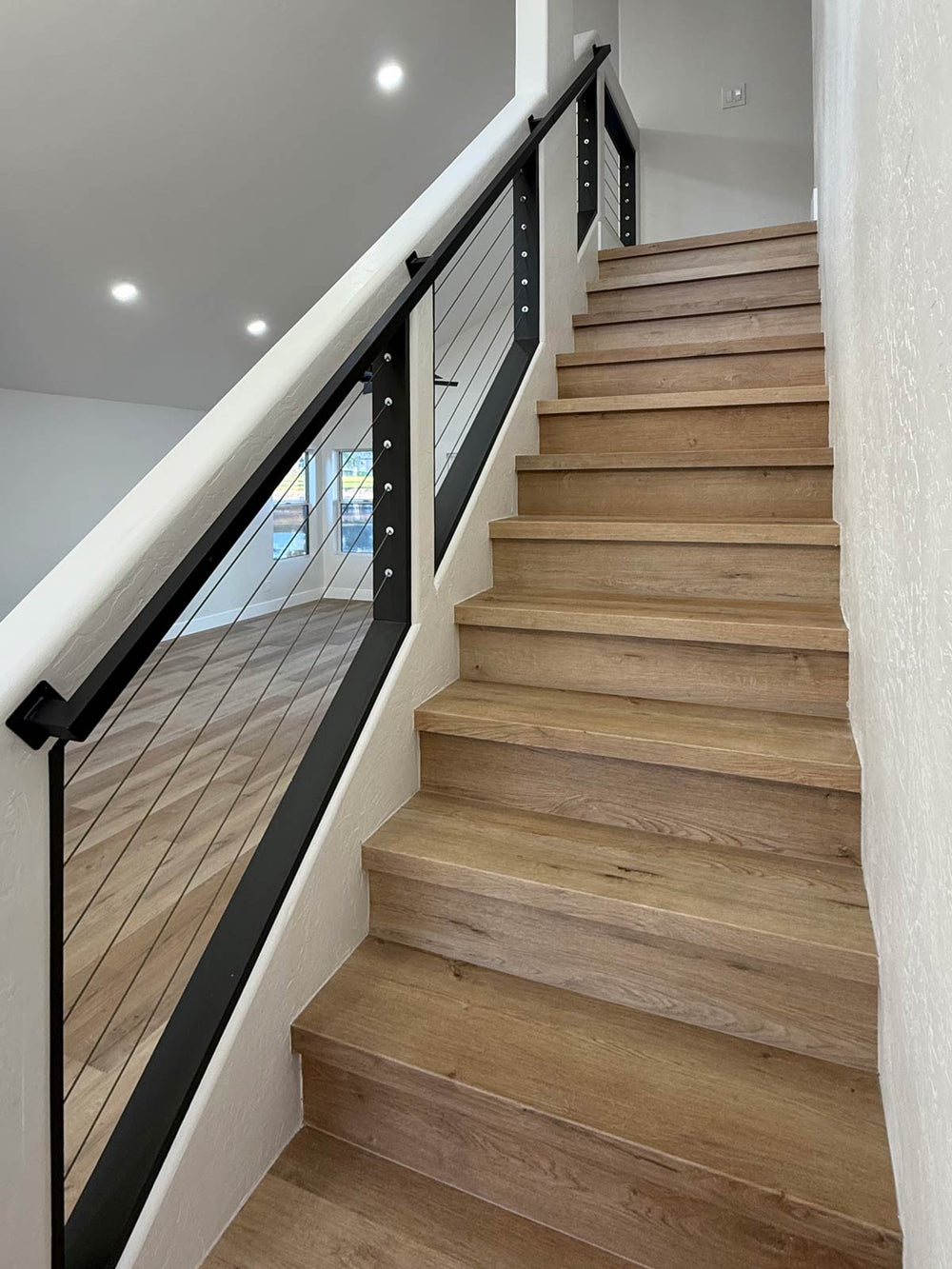 black cable stair railing paired with natural wood stairs in a modern interior