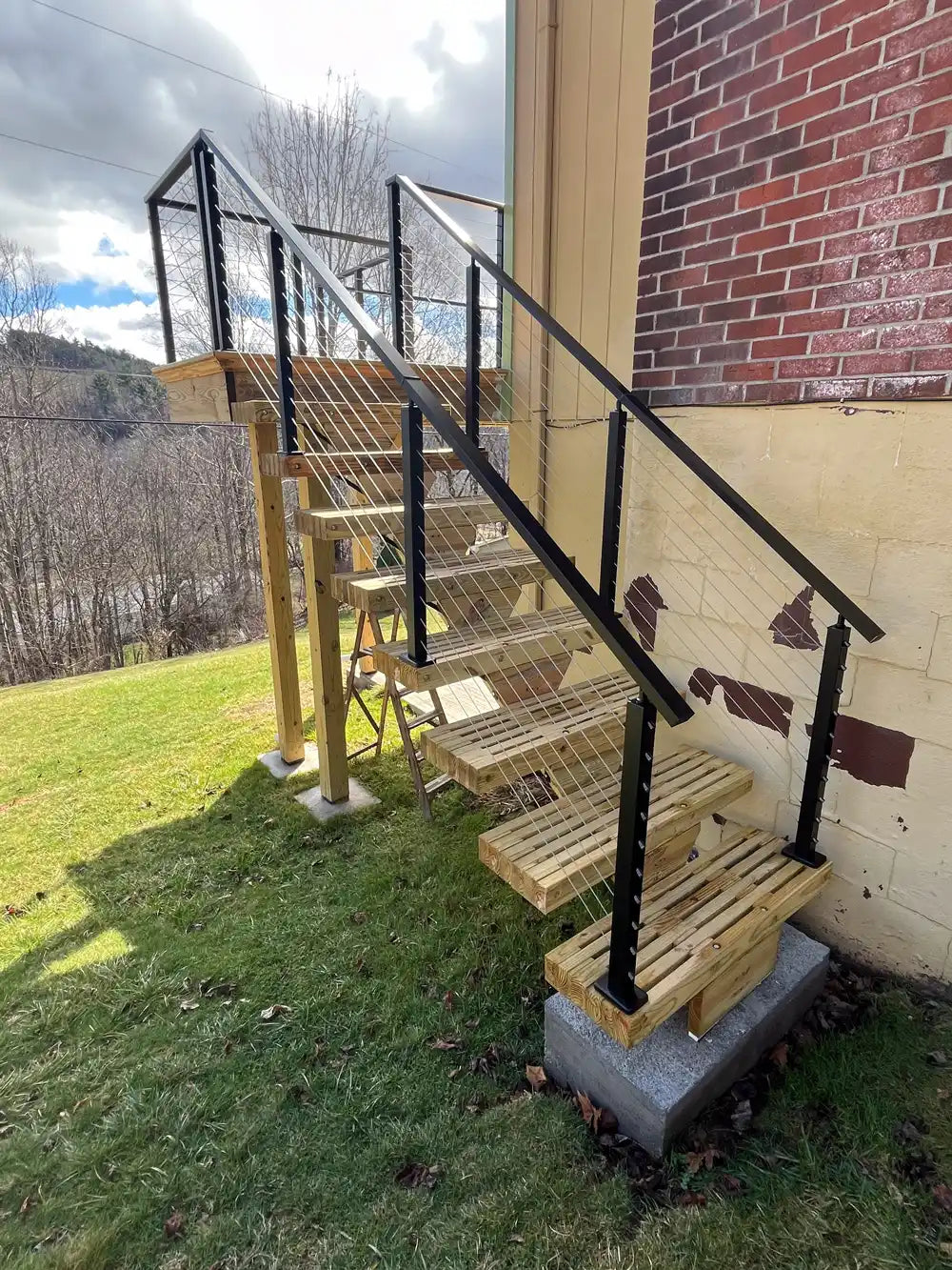 close-up-of-stairs-with-wire-deck-railing-and-grassy-yard