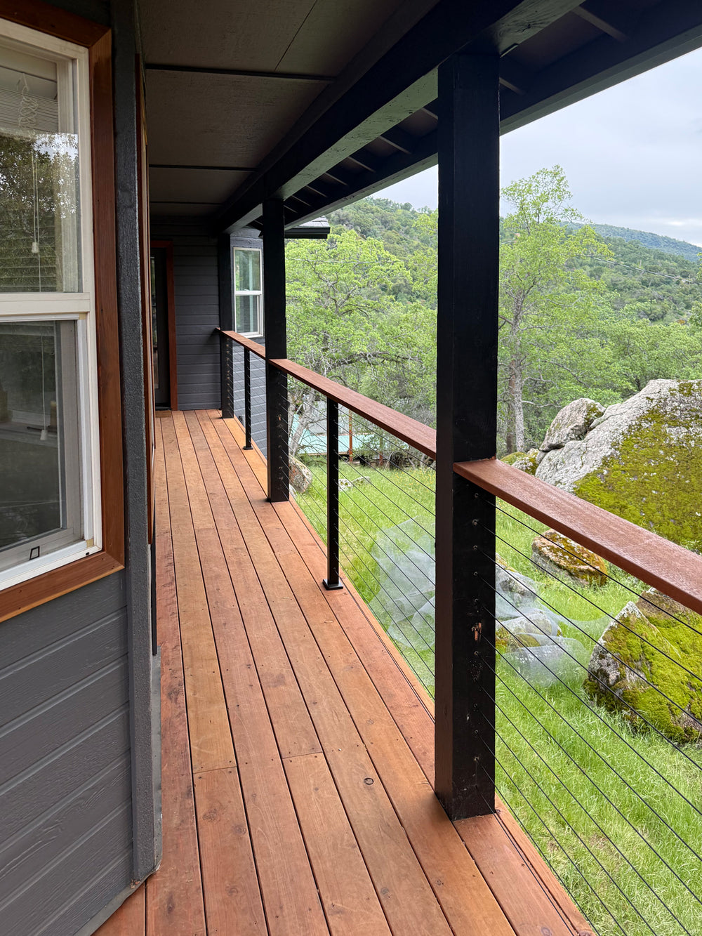 close-up of cable railing for decks on a wooden deck with natural views.