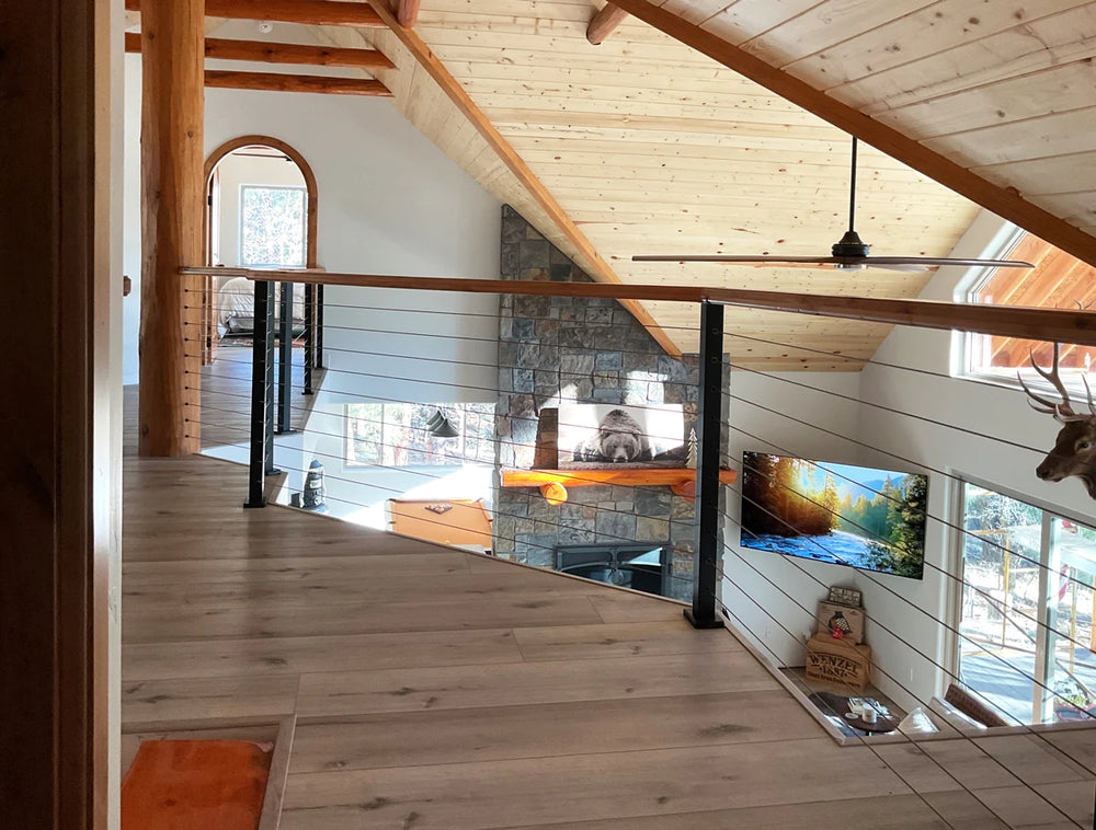 cozy loft interior with cable rail systems and stone fireplace