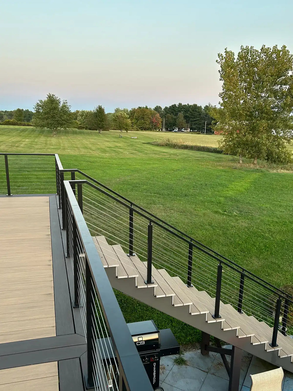 deck corner view showing wire deck railing running along the edge toward the open yard