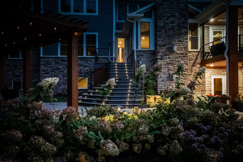 evening outdoor space featuring cable railing system, stone walls, and warm landscape lighting