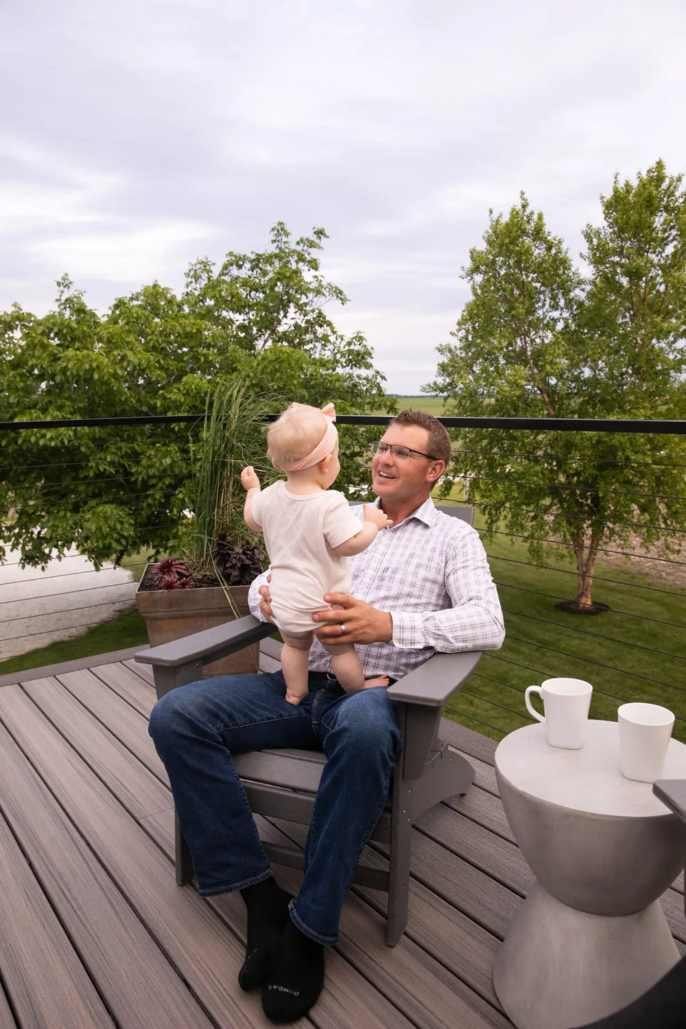 father-child-bond-on-deck-with-black-cable-railing-and-fields