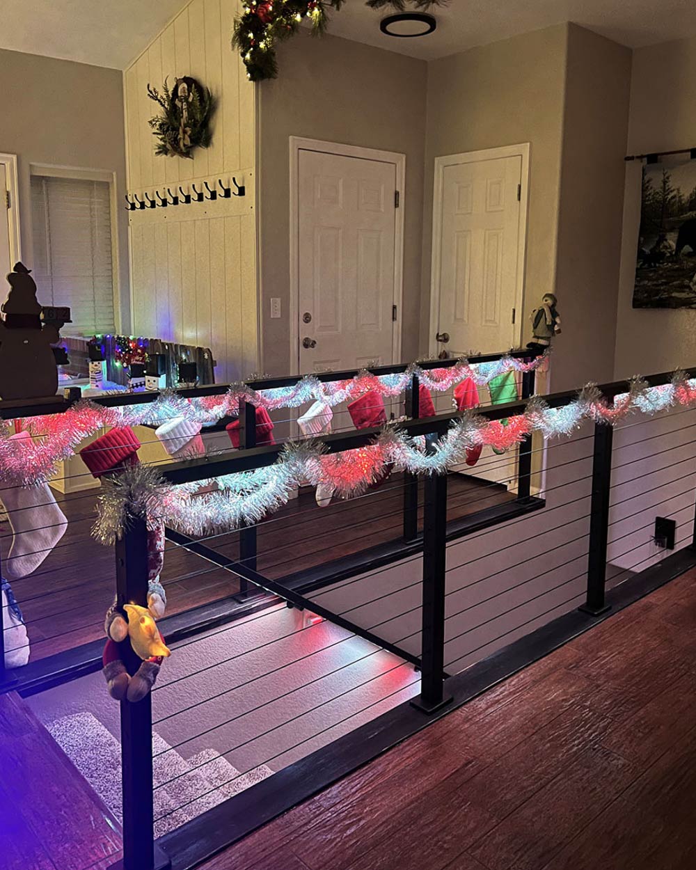 indoor cable railing decorated with christmas stockings and garland in cozy wyoming home