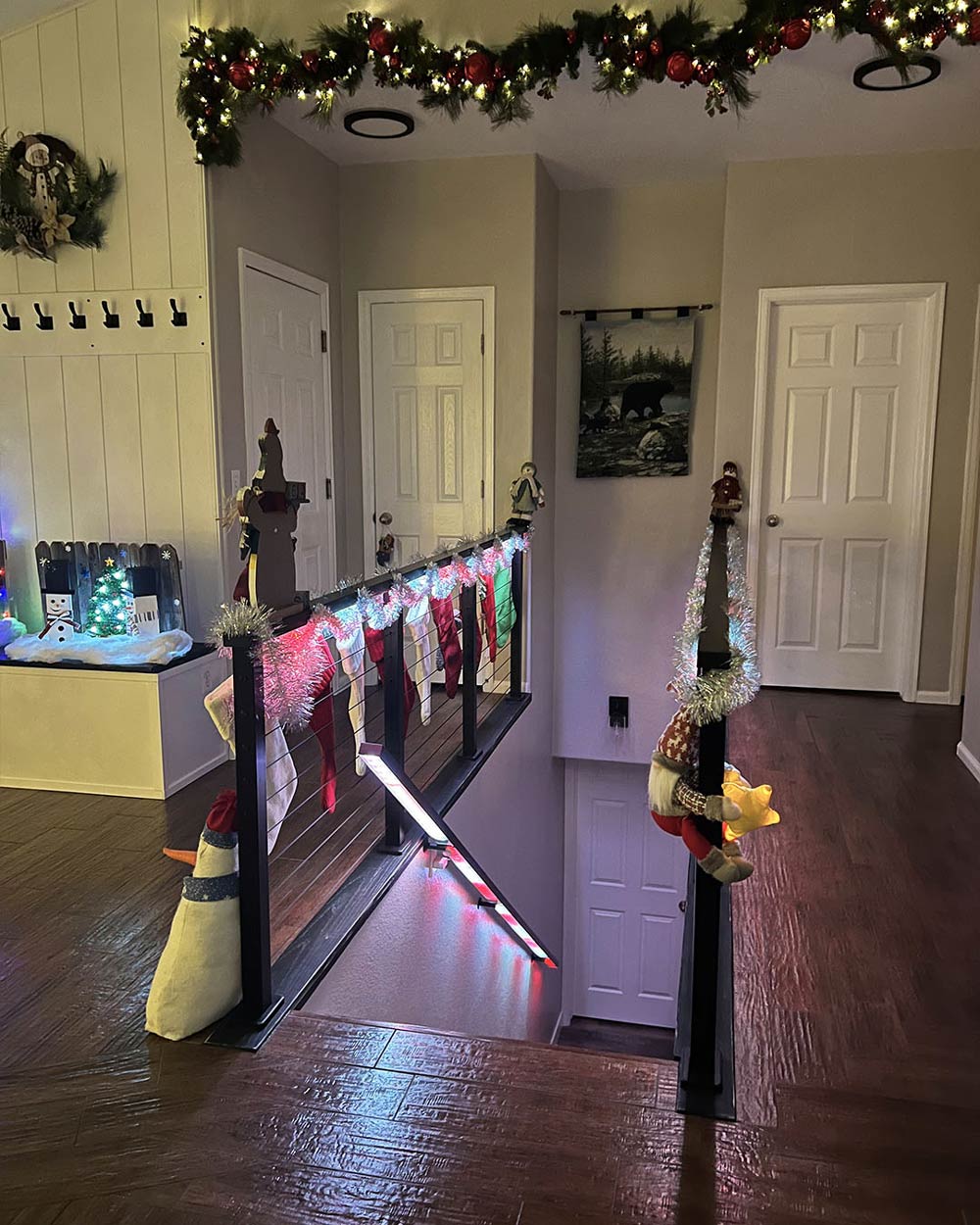 indoor cable railing staircase with holiday garland lights and family stockings