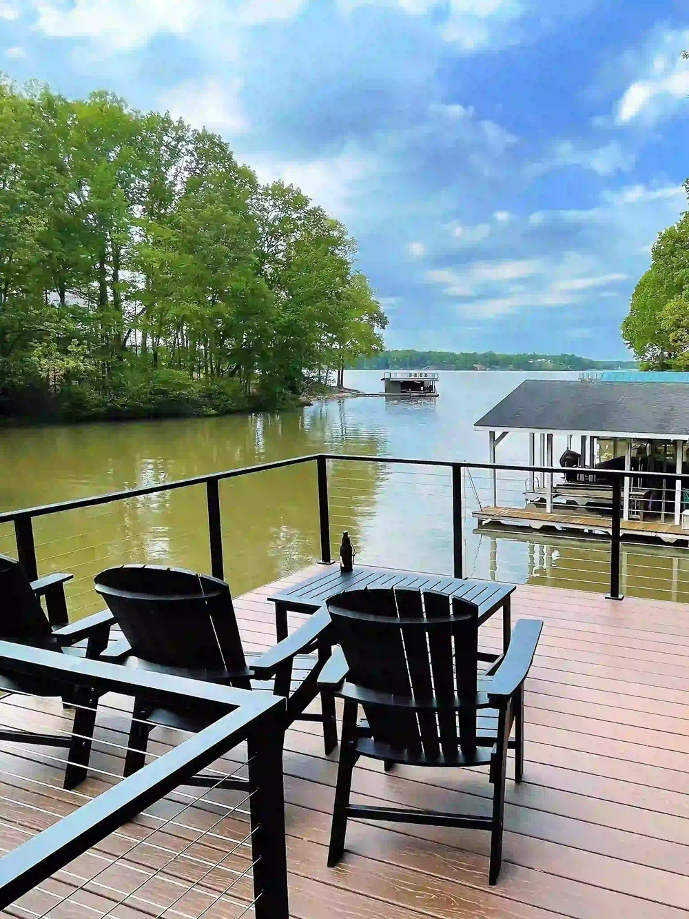 Waterfront boat dock with black cable railing overlooking the water and forest