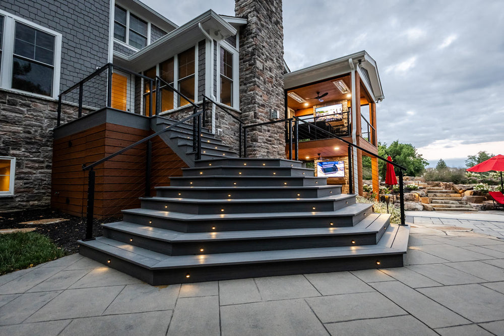 outdoor staircase with integrated step lighting and cable railing system beside the home