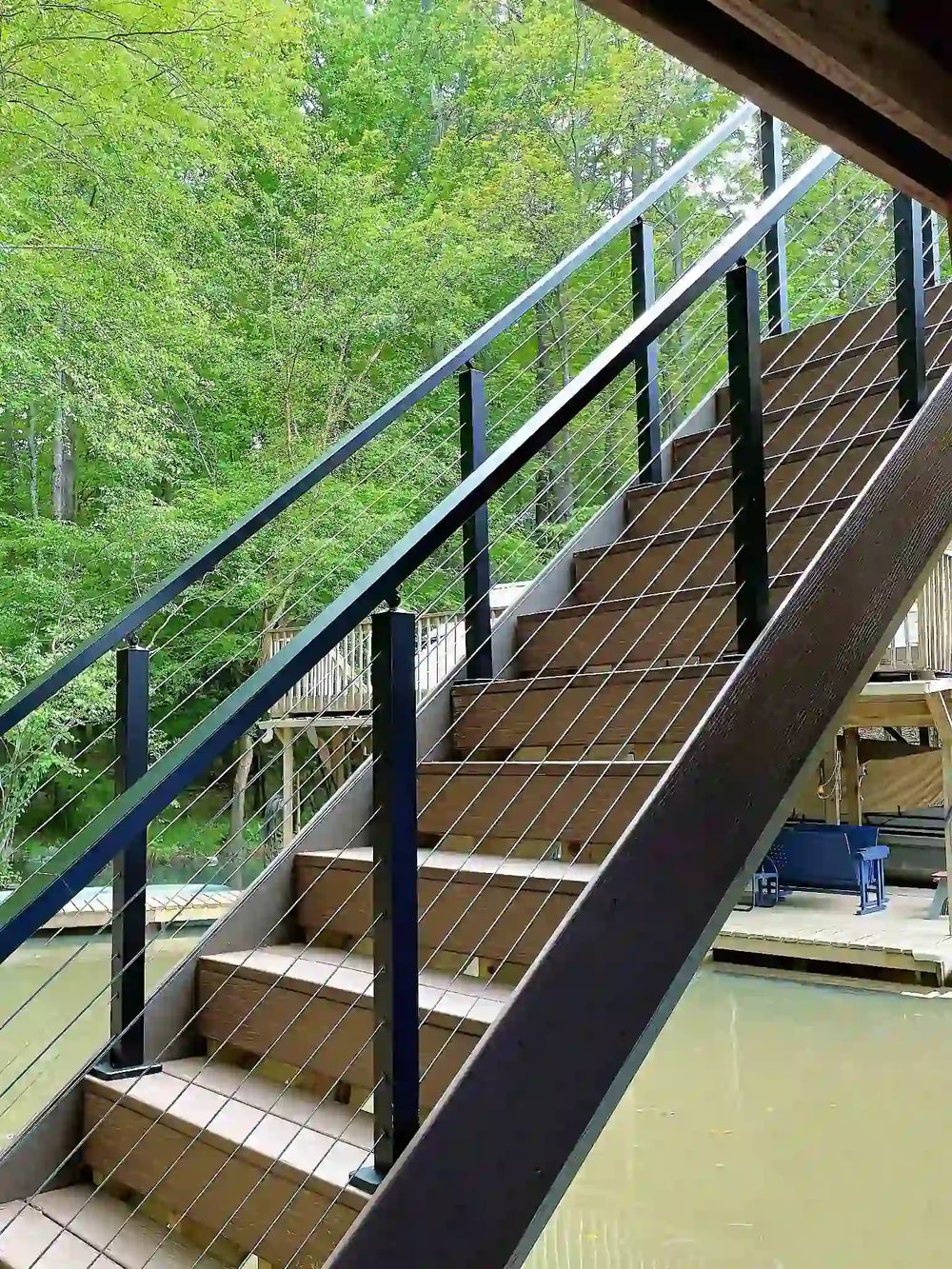 Modern outdoor staircase with black cable railing overlooking the lake