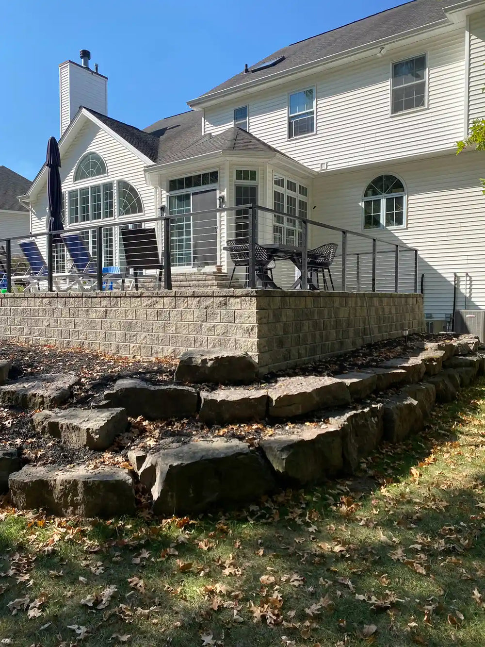side perspective of wire railing running along the edge of an elevated stone patio