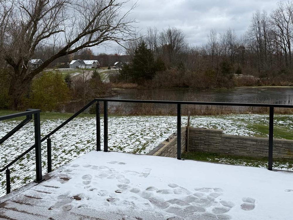 snow covered deck wire railing offering unobstructed pond and winter landscape view