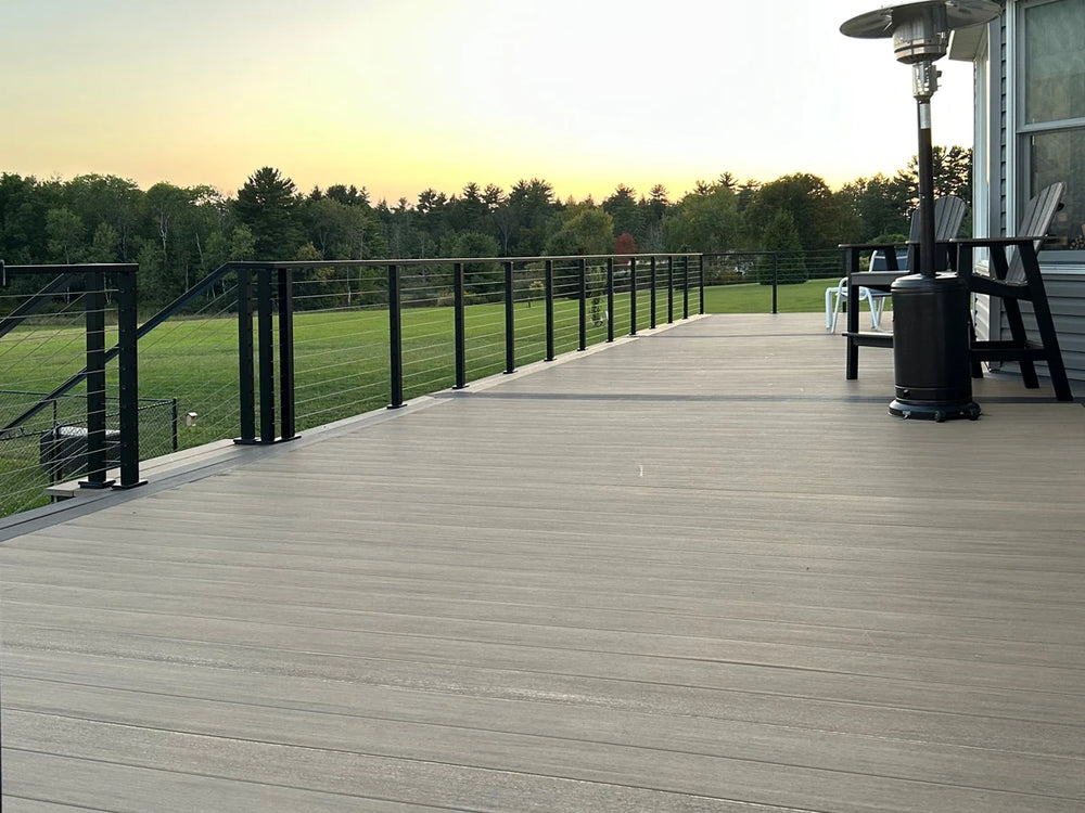 spacious deck with minimalist wire deck railing facing a large grassy yard