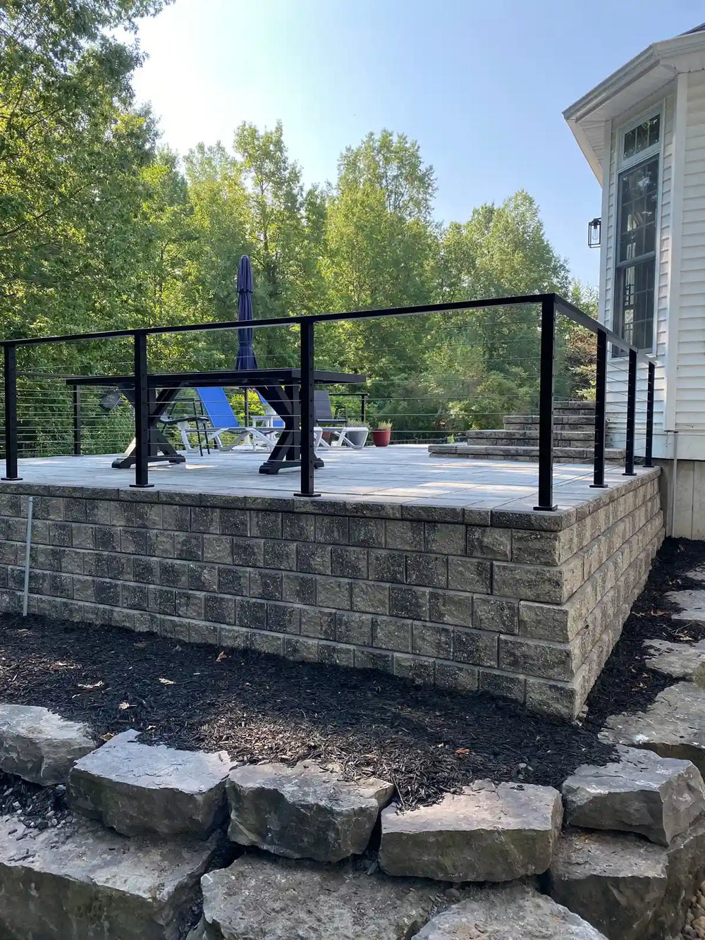 upper patio area featuring wire railing above layered stone landscaping