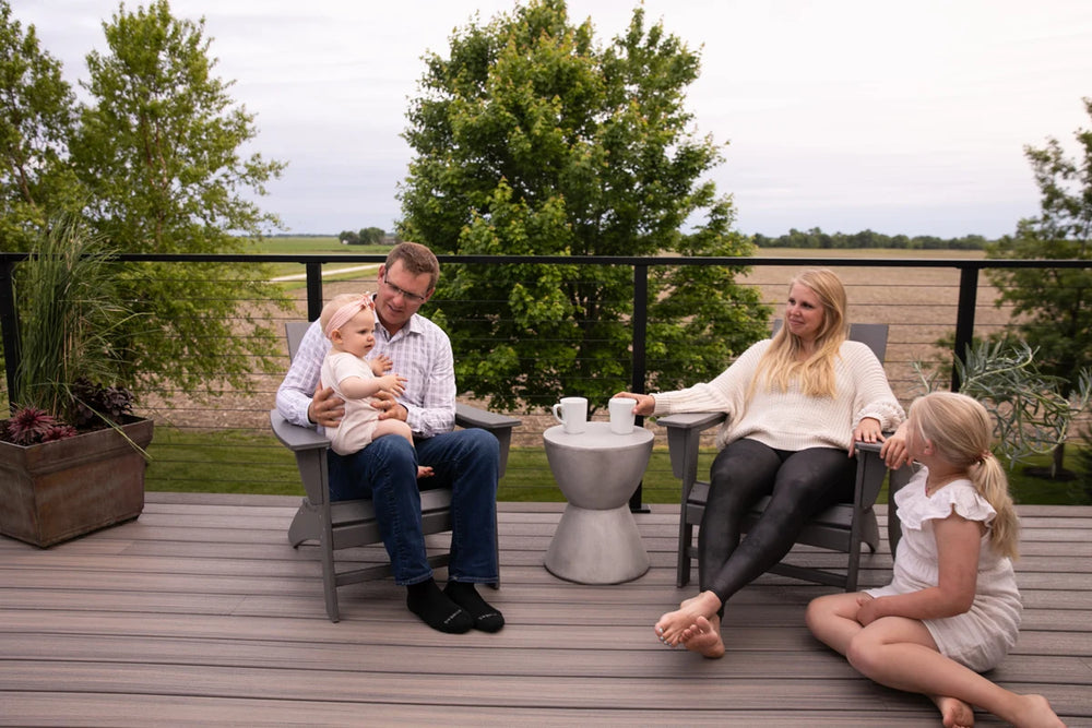 warm-family-bonding-on-deck-with-black-cable-railing-and-lush-trees