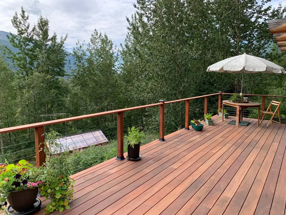 wide wood deck with cable railing and outdoor seating surrounded by trees