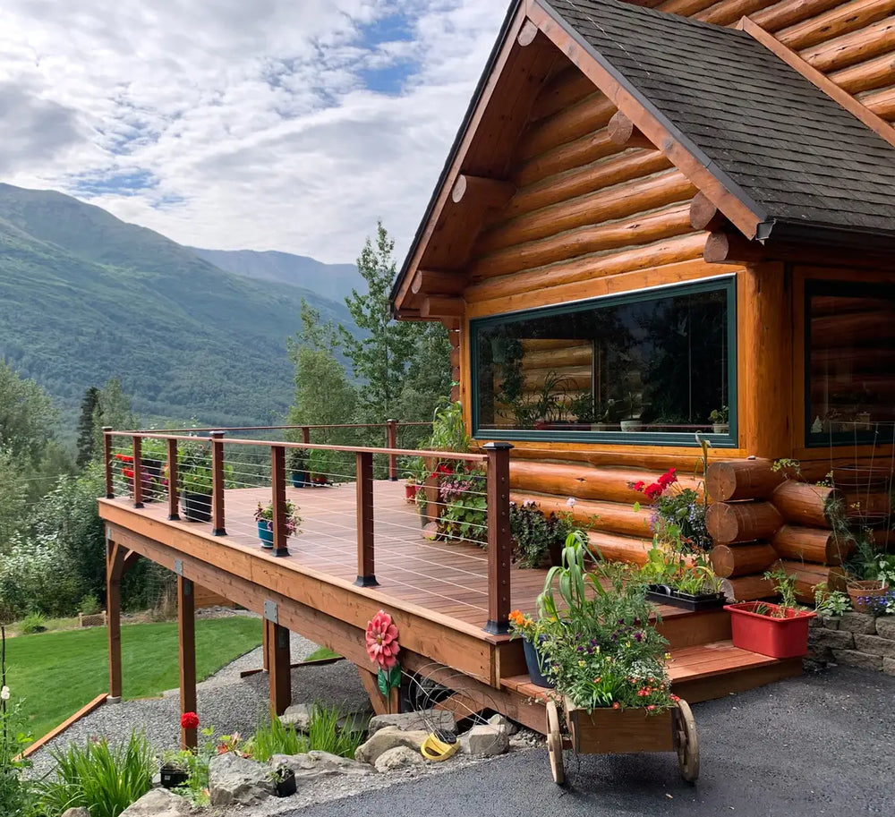 wood deck with cable railing beside a log-style home overlooking mountain scenery